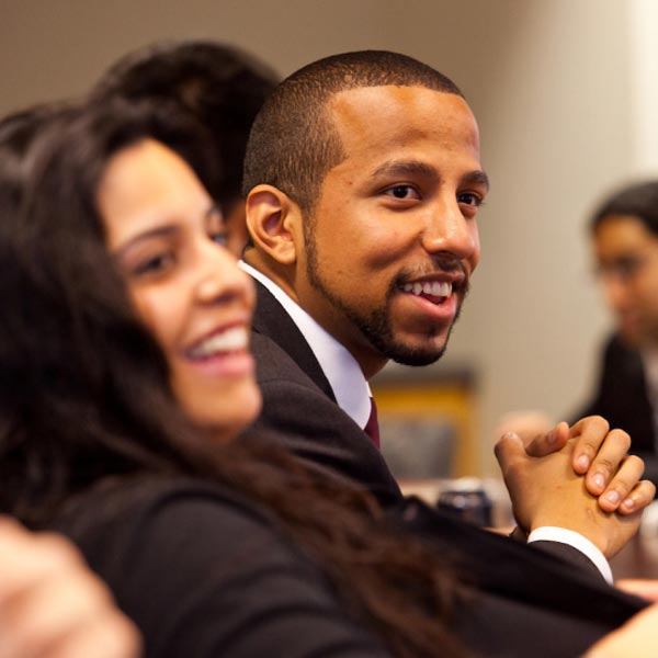 Close-up on two people in business setting, facing right, smiling