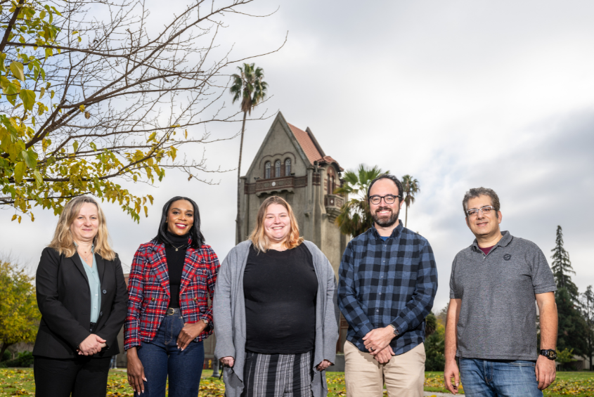 Staff members posing for a photograph in front of Tower Hall